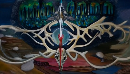 Artemis Goddess symbology. A still frame from a surreal animation: at the centre hangs a white stag skull with long, branching antlers forming an intricate, almost wing-like structure. Behind it glows a circular blue sphere, suggesting a portal or cosmic centre. At the top of the image is a dense, abstract forest rendered in luminous greens and blues, while the lower half shows layered landscapes in reds, browns, and purples, giving the scene a dreamlike, otherworldly quality. The composition is symmetrical and symbolic, blending natural imagery with a mystical, ritualistic atmosphere.